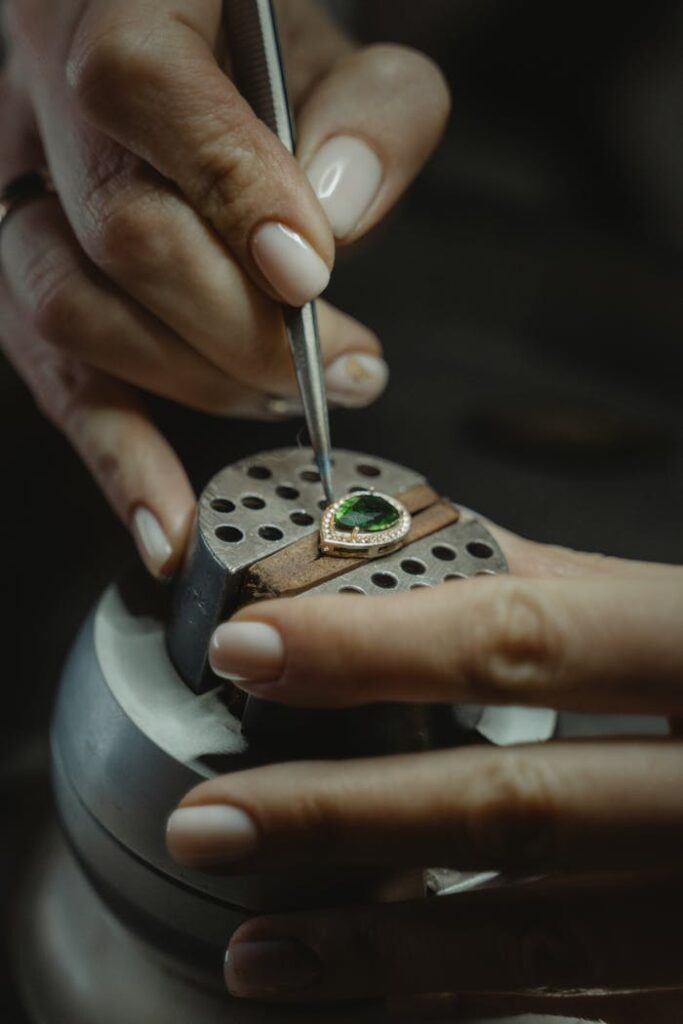 A skilled jeweler carefully crafting an emerald ring using a tweezer, showcasing Ceylon craftsmanship.